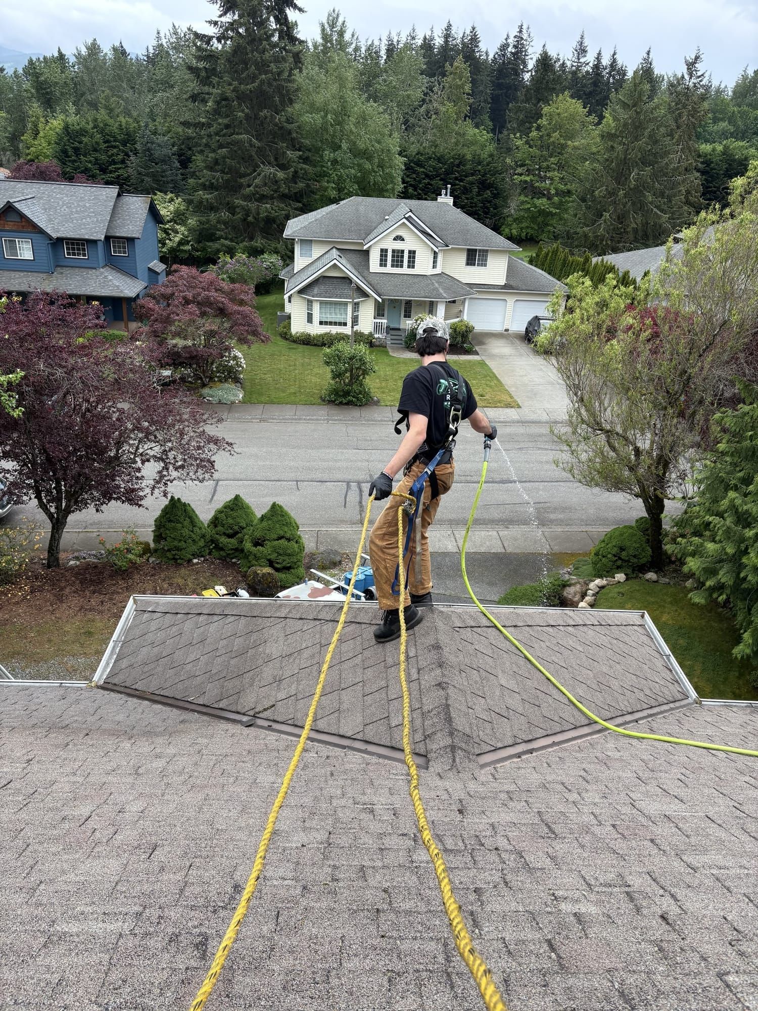 Rainlife Washing technician rinsing a roof during soft wash treatment